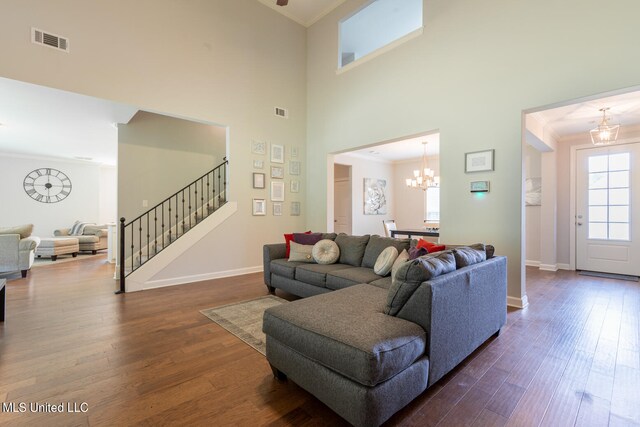 living room with ornamental molding, dark hardwood / wood-style floors, a chandelier, and a high ceiling