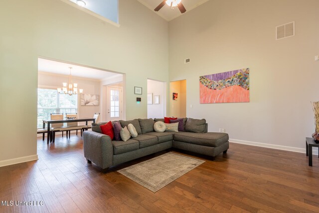 living room with crown molding, dark hardwood / wood-style floors, ceiling fan with notable chandelier, and a high ceiling