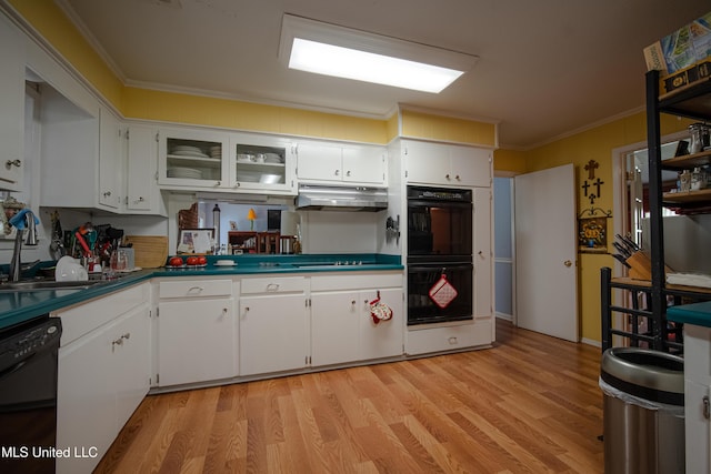 kitchen featuring crown molding, a sink, light wood finished floors, under cabinet range hood, and black appliances