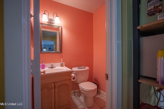 half bath with tile patterned floors, toilet, baseboards, and vanity