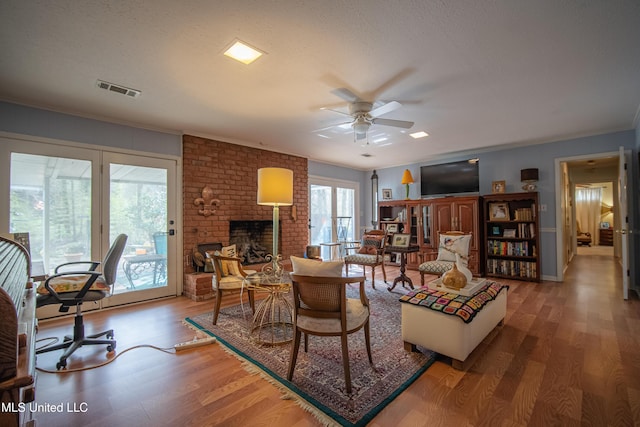 living area featuring visible vents, a textured ceiling, wood finished floors, and a ceiling fan