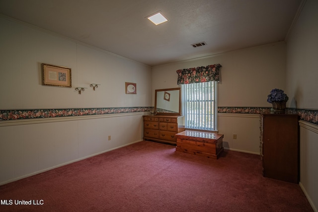 unfurnished bedroom featuring visible vents, crown molding, carpet, and wainscoting