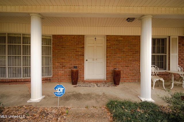 entrance to property with covered porch and brick siding