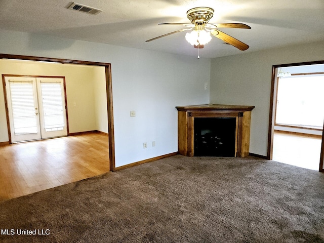 unfurnished living room featuring ceiling fan, french doors, light carpet, and a healthy amount of sunlight