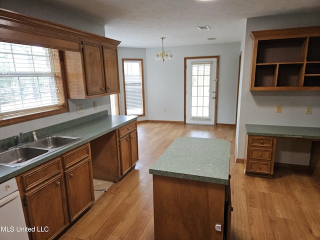 kitchen featuring sink, hanging light fixtures, built in desk, and light wood-type flooring