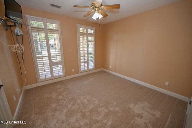 carpeted spare room with ceiling fan and a textured ceiling