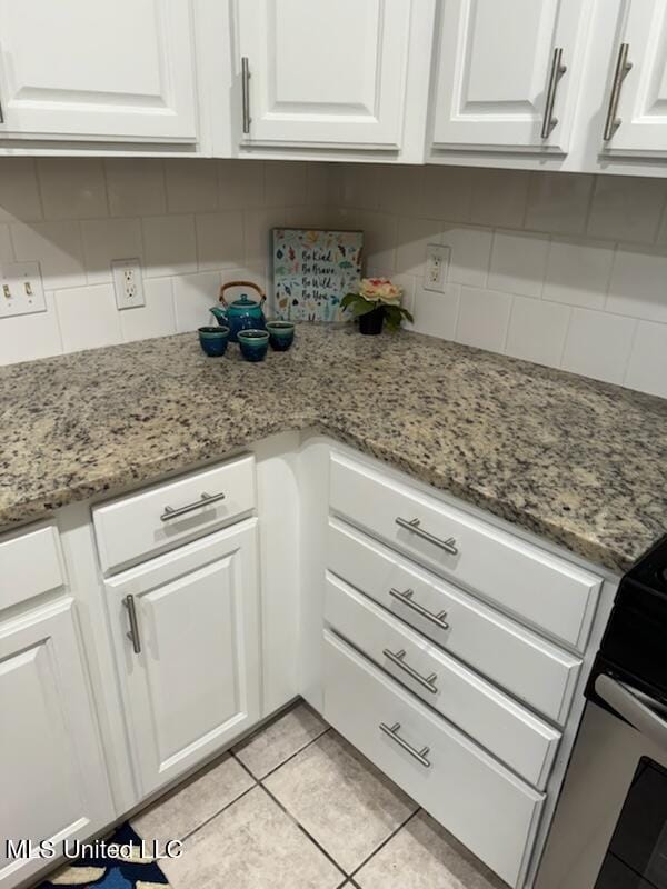 kitchen with white cabinetry, light stone countertops, and light tile patterned flooring