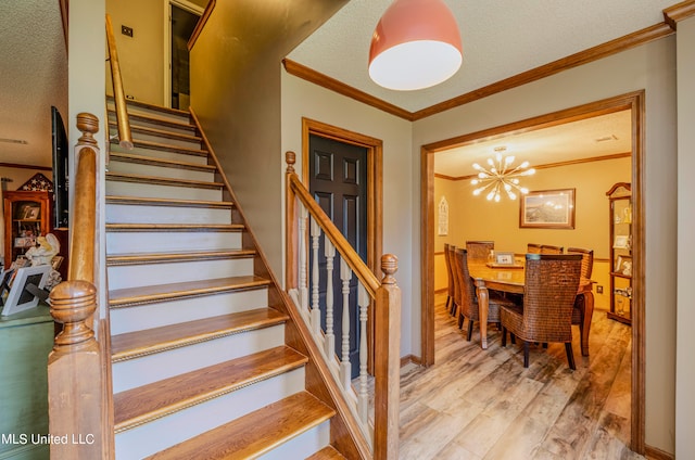 staircase with hardwood / wood-style floors, a notable chandelier, crown molding, and a textured ceiling