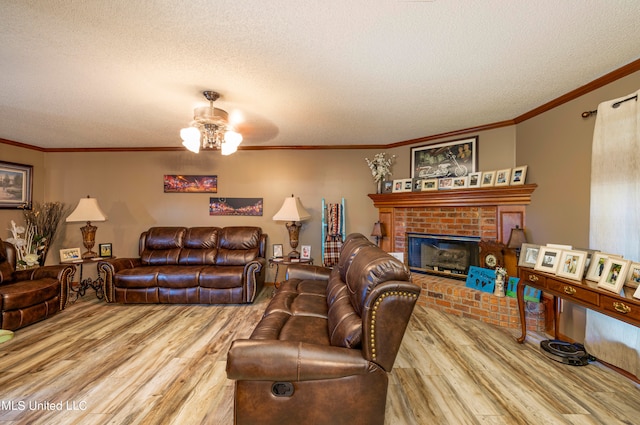 living room with ceiling fan, a textured ceiling, hardwood / wood-style flooring, a brick fireplace, and ornamental molding