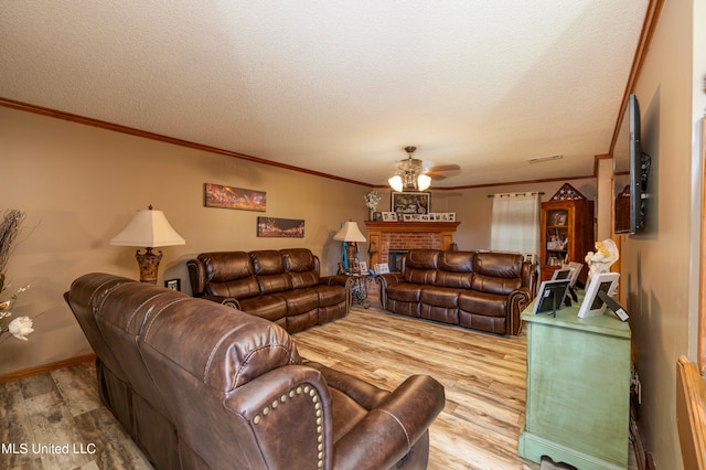 living room featuring crown molding, a brick fireplace, light wood-type flooring, a textured ceiling, and ceiling fan