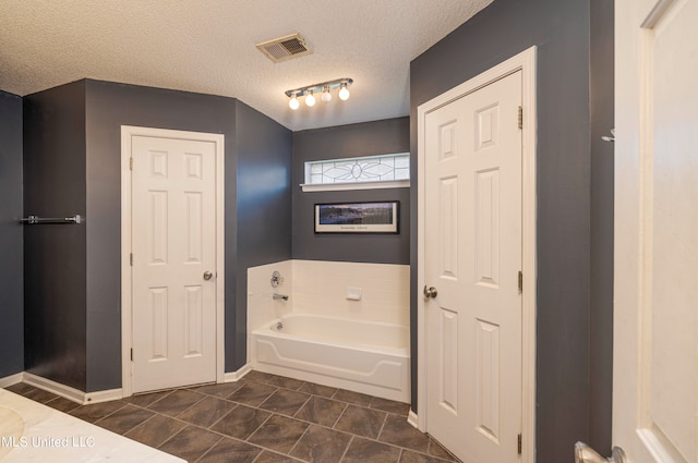 bathroom featuring a tub, a textured ceiling, and tile patterned flooring