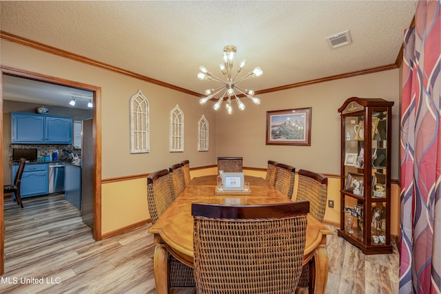 dining space featuring ornamental molding, an inviting chandelier, a textured ceiling, and light wood-type flooring