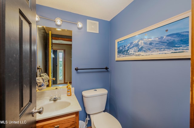 bathroom with toilet, a textured ceiling, and vanity