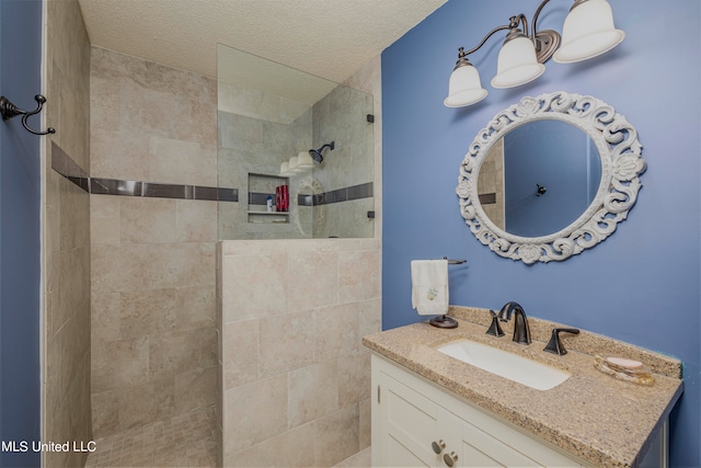 bathroom with vanity, a tile shower, and a textured ceiling