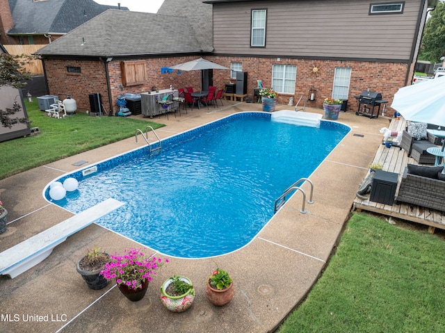 view of pool featuring a patio area, a diving board, a lawn, and a grill