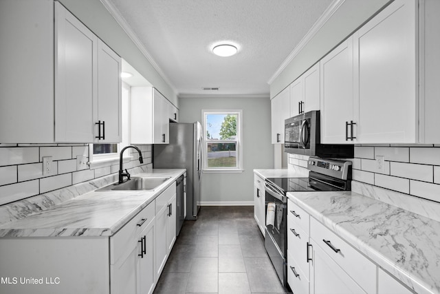 kitchen with appliances with stainless steel finishes, sink, a textured ceiling, tile patterned floors, and white cabinets