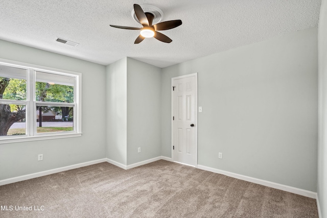 carpeted spare room featuring ceiling fan and a textured ceiling