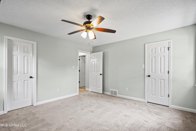 unfurnished bedroom featuring ceiling fan, a textured ceiling, and light colored carpet