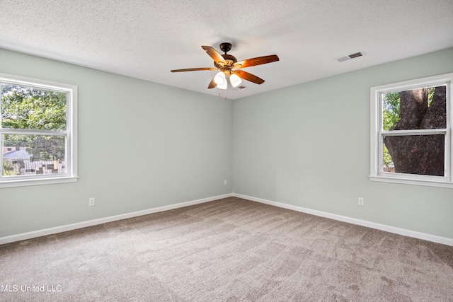 carpeted empty room with ceiling fan, a healthy amount of sunlight, and a textured ceiling