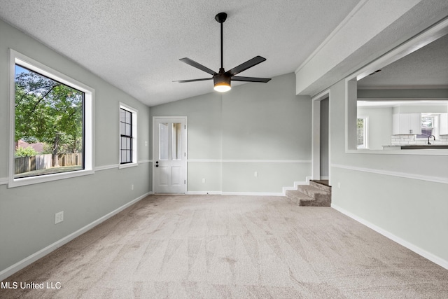 spare room featuring a textured ceiling, ceiling fan, carpet, and vaulted ceiling