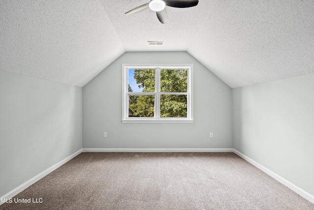 bonus room featuring carpet flooring, a textured ceiling, vaulted ceiling, and ceiling fan