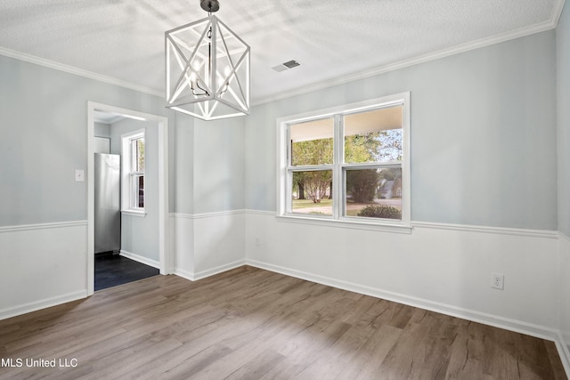 spare room with ornamental molding, a textured ceiling, hardwood / wood-style flooring, and a chandelier