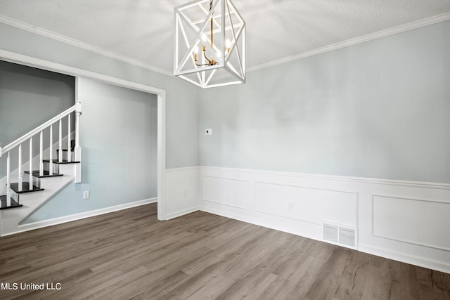 empty room featuring ornamental molding, a chandelier, hardwood / wood-style flooring, and a textured ceiling