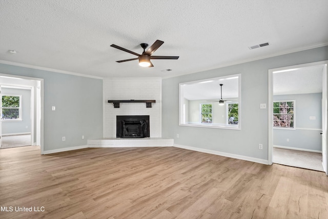 unfurnished living room with a fireplace, a textured ceiling, plenty of natural light, and light wood-type flooring