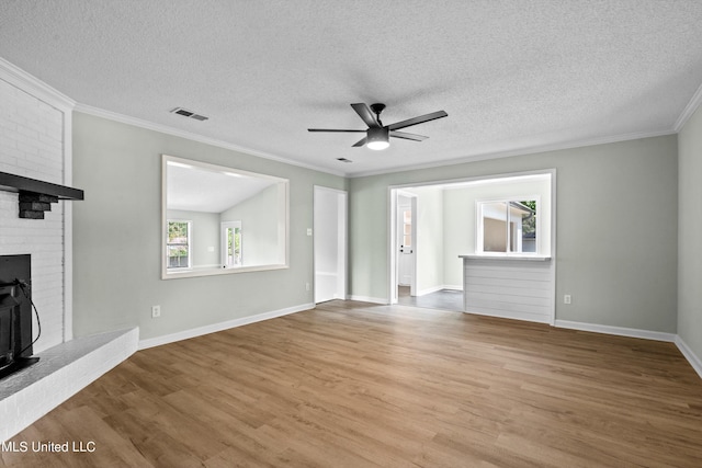 unfurnished living room with a fireplace, a textured ceiling, light wood-type flooring, and crown molding