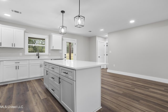 1457 Rue De Courmont, Gautier, MS 39553 - kitchen with recessed lighting, dark wood finished floors, white cabinets, light countertops, and a center island