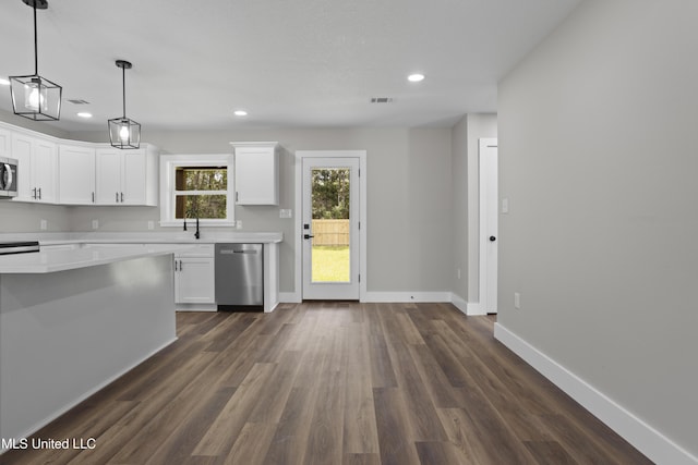 1457 Rue De Courmont, Gautier, MS 39553 - kitchen with stainless steel appliances, light countertops, dark wood-style floors, recessed lighting, and white cabinets