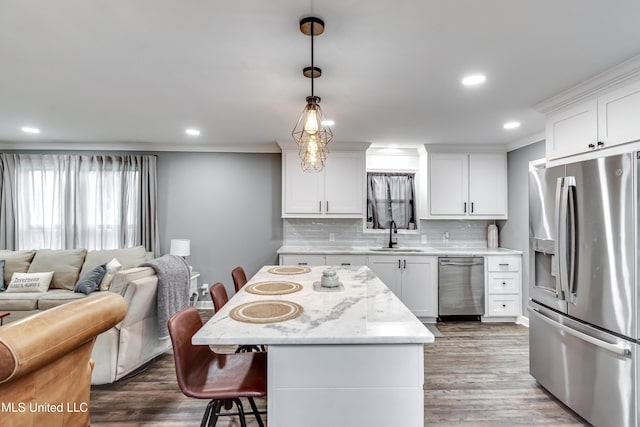 kitchen featuring white cabinetry, stainless steel appliances, sink, and hanging light fixtures