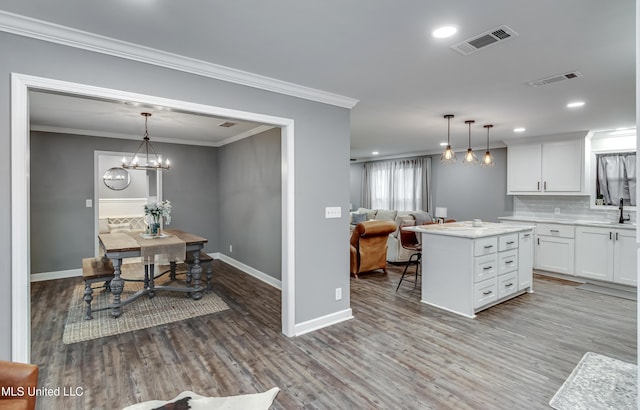 kitchen with white cabinetry, ornamental molding, hanging light fixtures, and a kitchen island