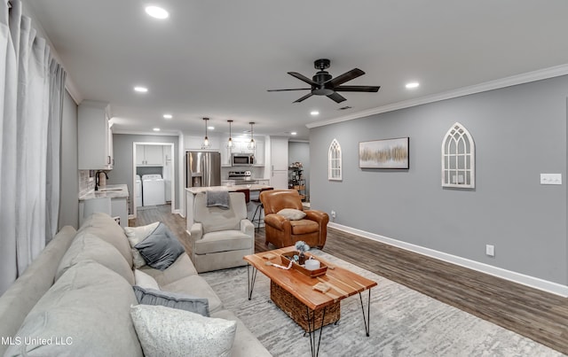 living room featuring crown molding, sink, light hardwood / wood-style floors, and washing machine and dryer