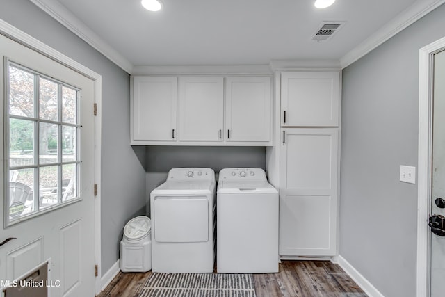 clothes washing area featuring cabinets, washing machine and dryer, and light wood-type flooring