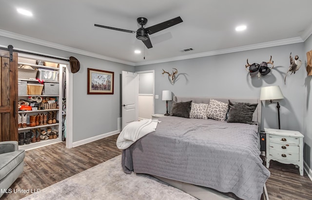 bedroom featuring dark hardwood / wood-style floors, ceiling fan, ornamental molding, and a barn door