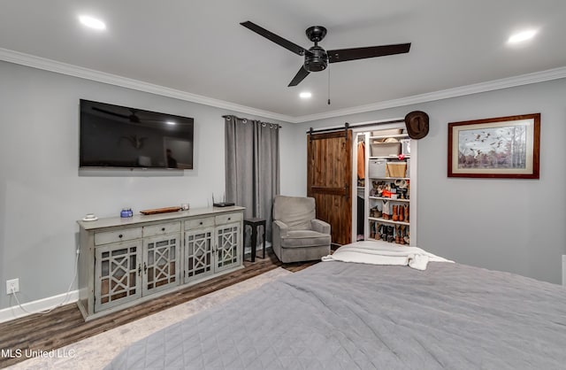 bedroom featuring wood-type flooring, ornamental molding, and a barn door