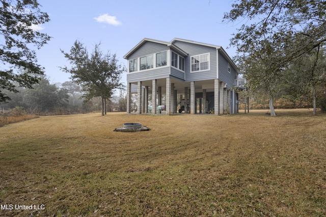 exterior space featuring a sunroom, a front yard, and an outdoor fire pit