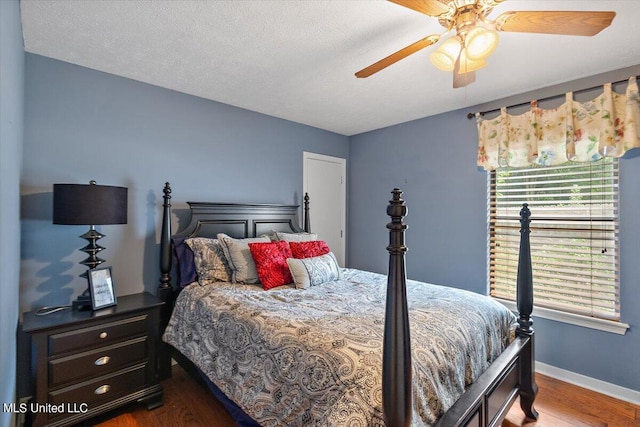 bedroom with a textured ceiling, wood-type flooring, and ceiling fan