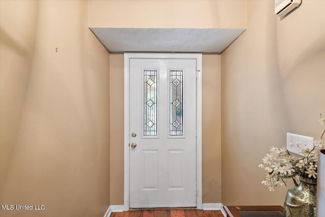 foyer entrance featuring an AC wall unit, a textured ceiling, and hardwood / wood-style floors