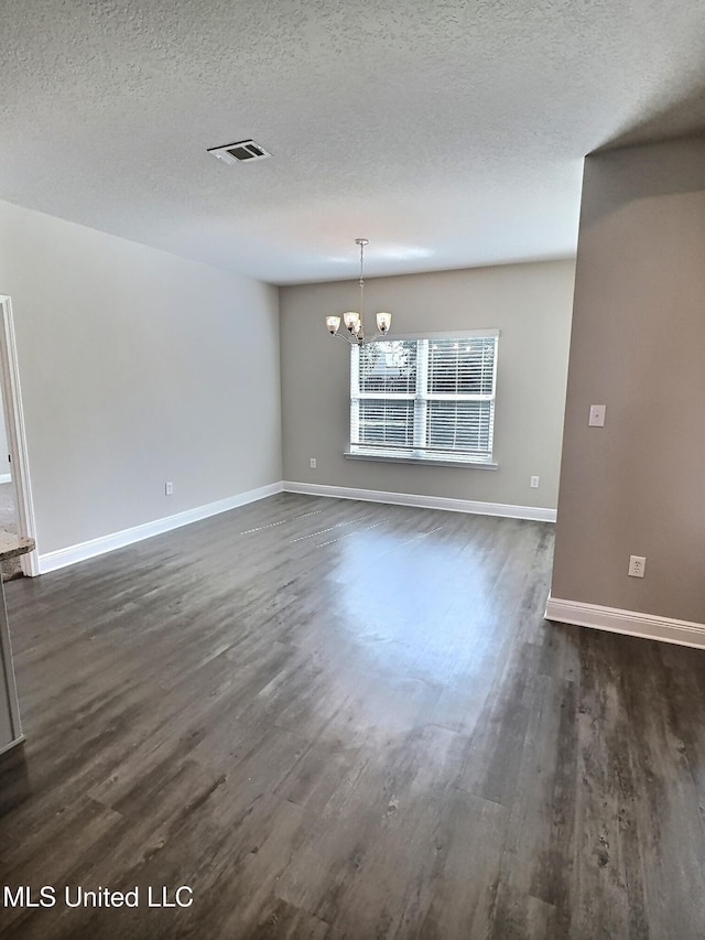 unfurnished dining area with baseboards, dark wood finished floors, a textured ceiling, and a chandelier