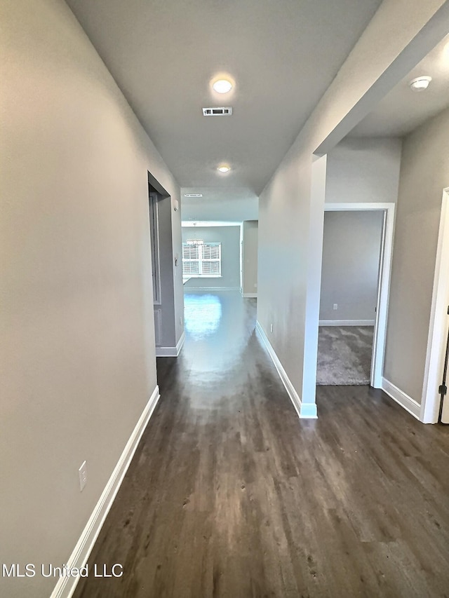 hallway with baseboards, visible vents, and dark wood-type flooring