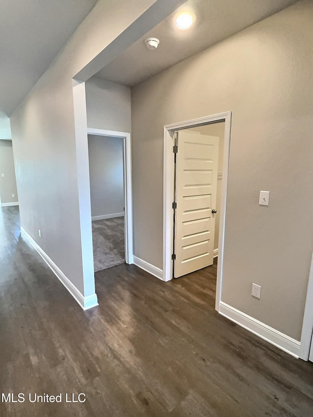 empty room featuring baseboards and dark wood finished floors