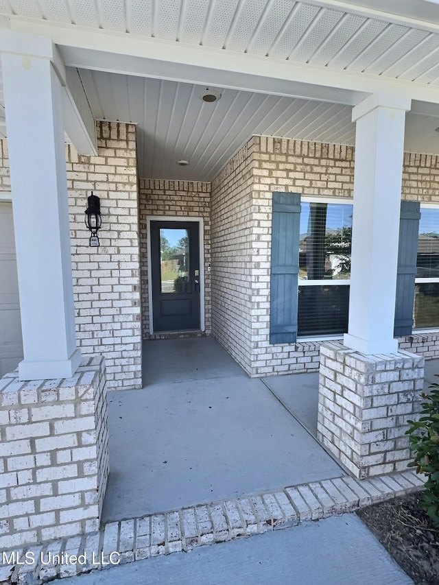 doorway to property with covered porch and brick siding