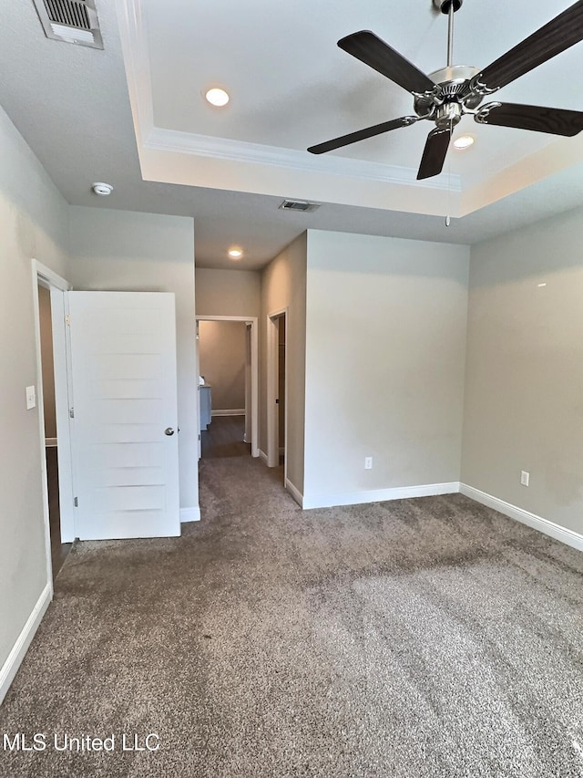 spare room featuring a raised ceiling, carpet flooring, recessed lighting, and visible vents
