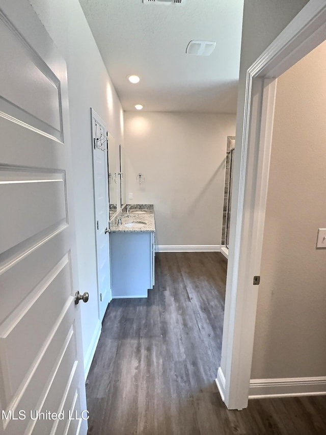 clothes washing area featuring dark wood-type flooring, a sink, and baseboards