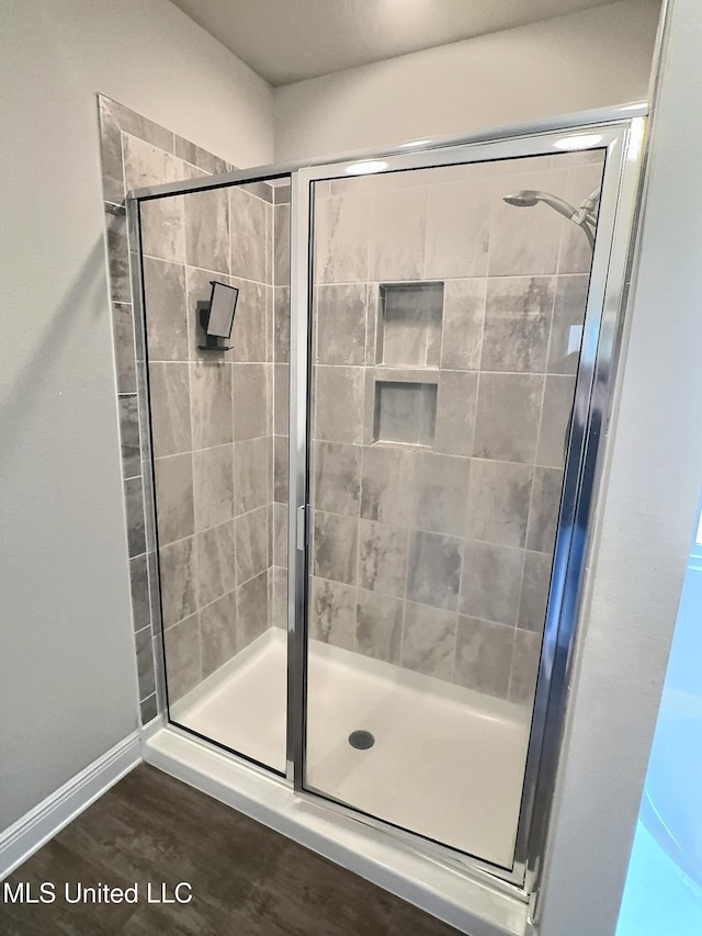 bathroom with baseboards, wood finished floors, and a stall shower