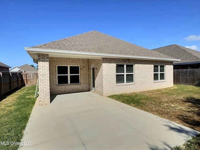 back of property with a yard, a patio, a shingled roof, and a fenced backyard