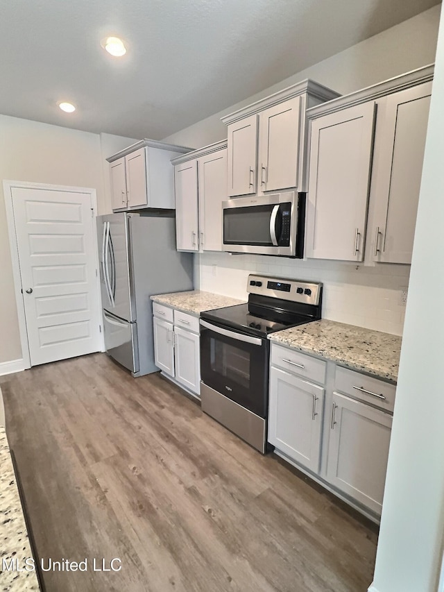 kitchen with decorative backsplash, wood finished floors, light stone countertops, recessed lighting, and stainless steel appliances