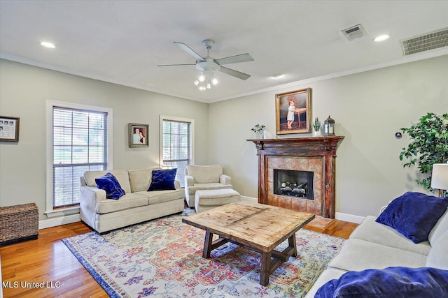 501 Brighton Cir, Brandon, MS 39047 - living room with a ceiling fan, light wood finished floors, a tiled fireplace, ornamental molding, and baseboards